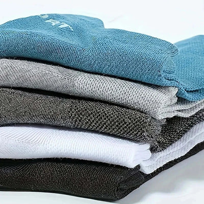 Stack of trendy men’s low cut socks in blue, gray, white, and black, made from high-quality breathable material.